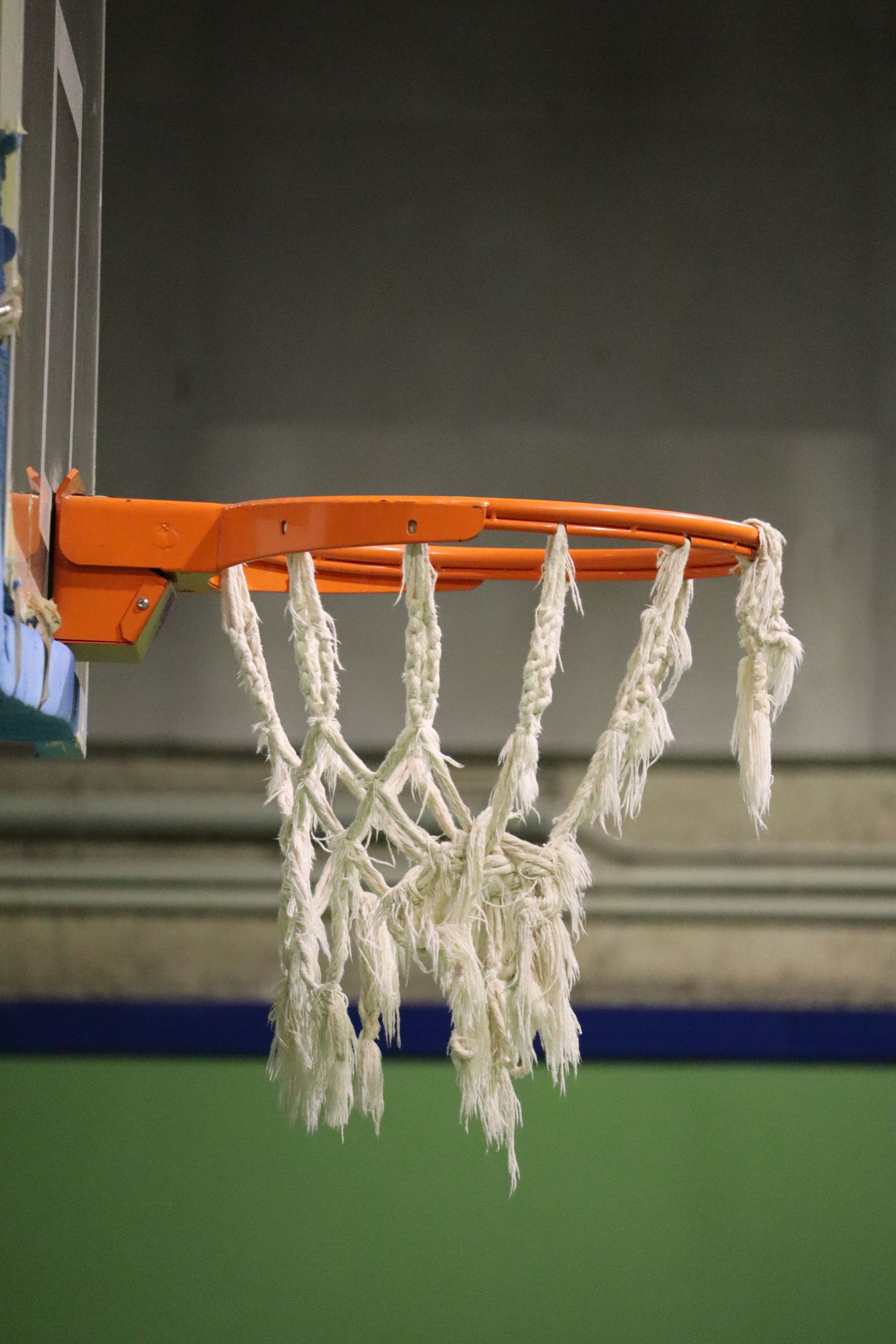 Close view of an orange basketball rim and white net from underneath