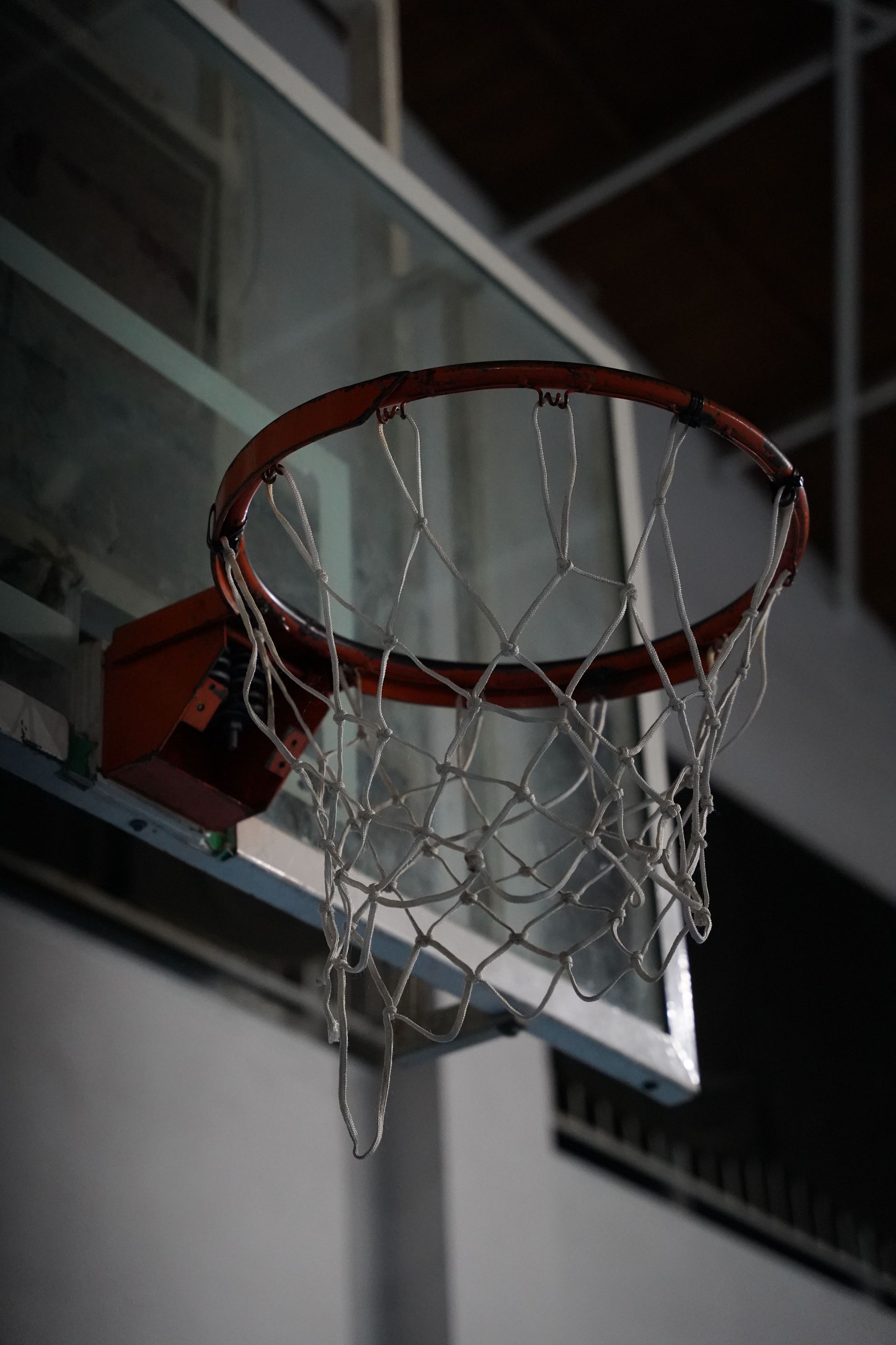 Basketball rim and net viewed from below against an arena roof structure