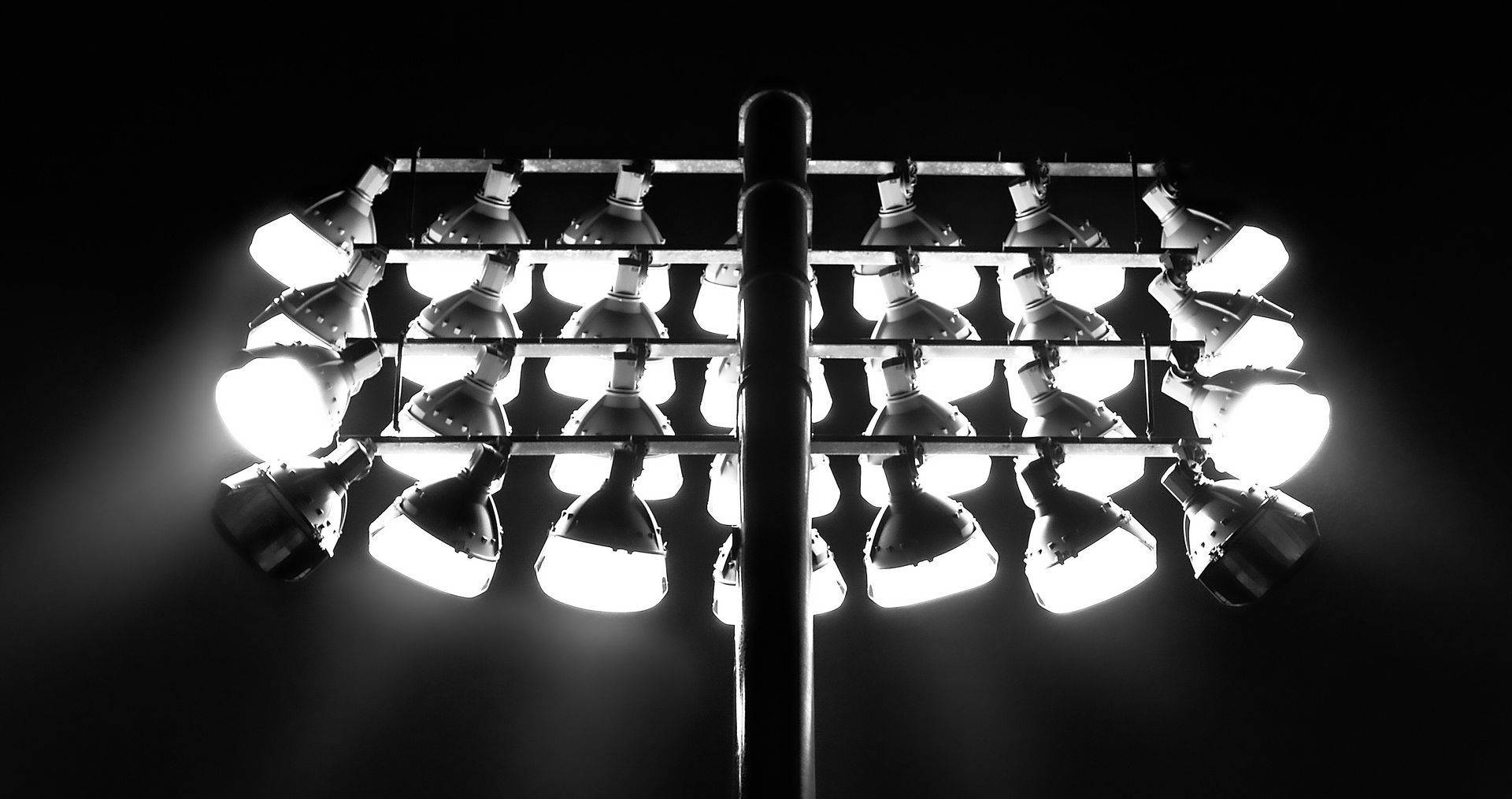 Close view of a bank of stadium floodlights glowing against a black night sky