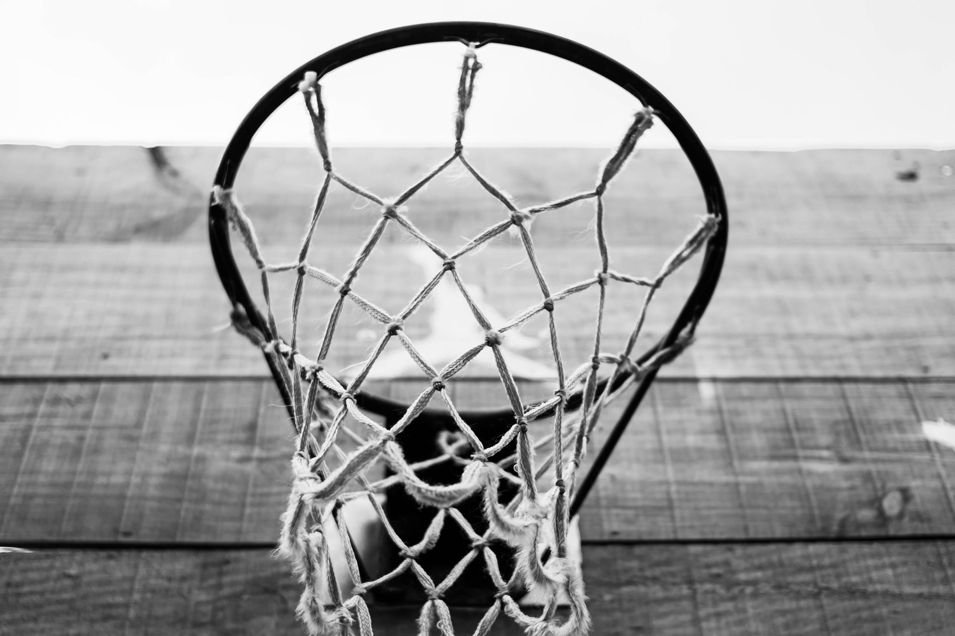 Black and white view of a basketball rim and net from below the backboard
