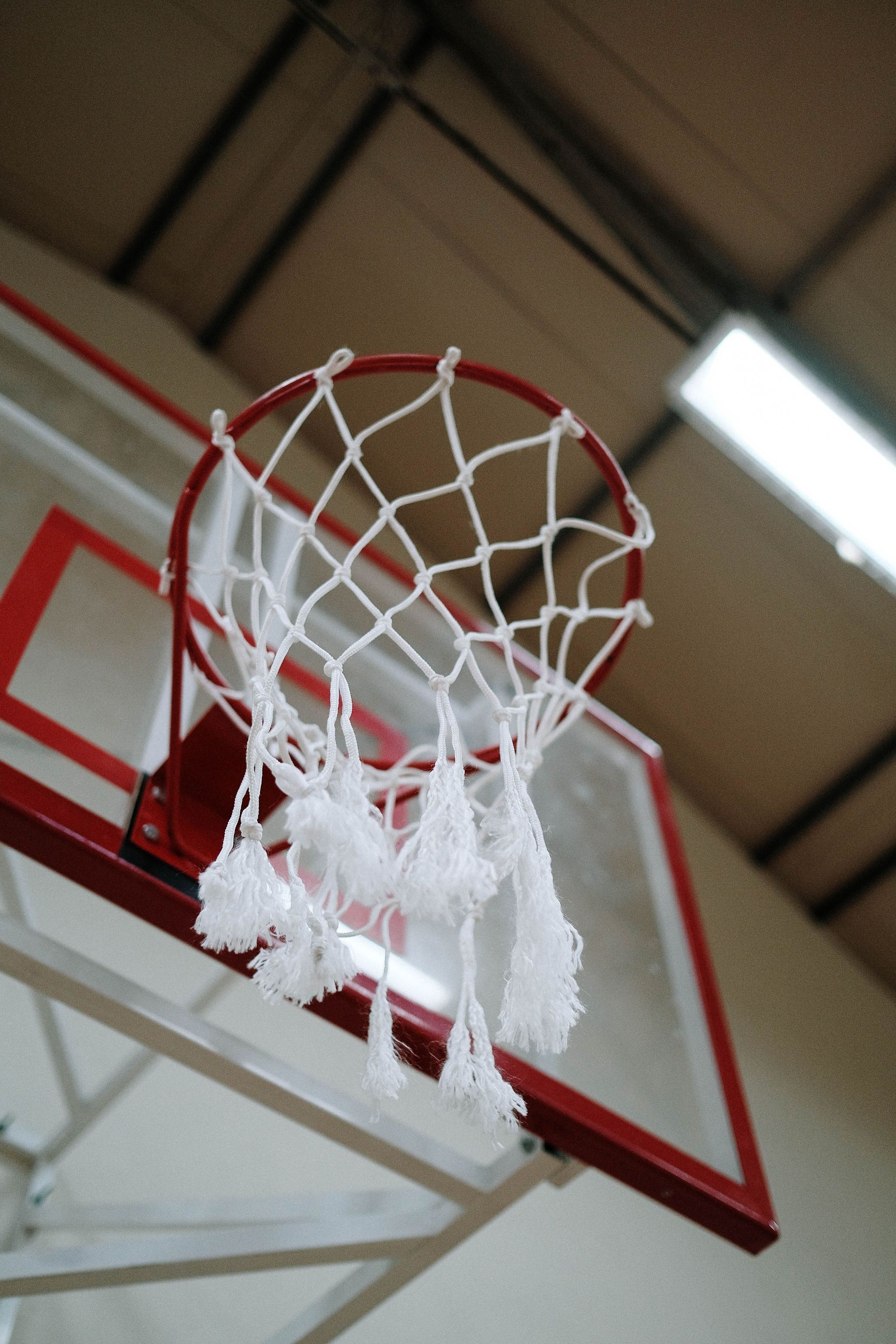 Basketball backboard and net lit by skylights in an indoor sports hall