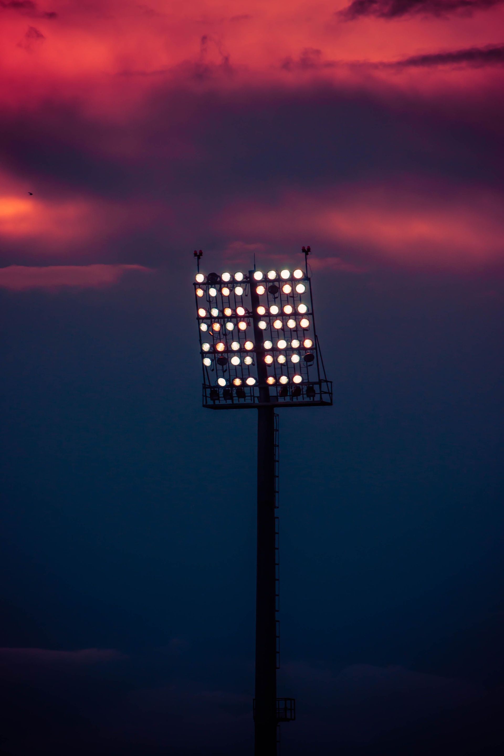 Stadium floodlights glowing beneath purple storm clouds at dusk