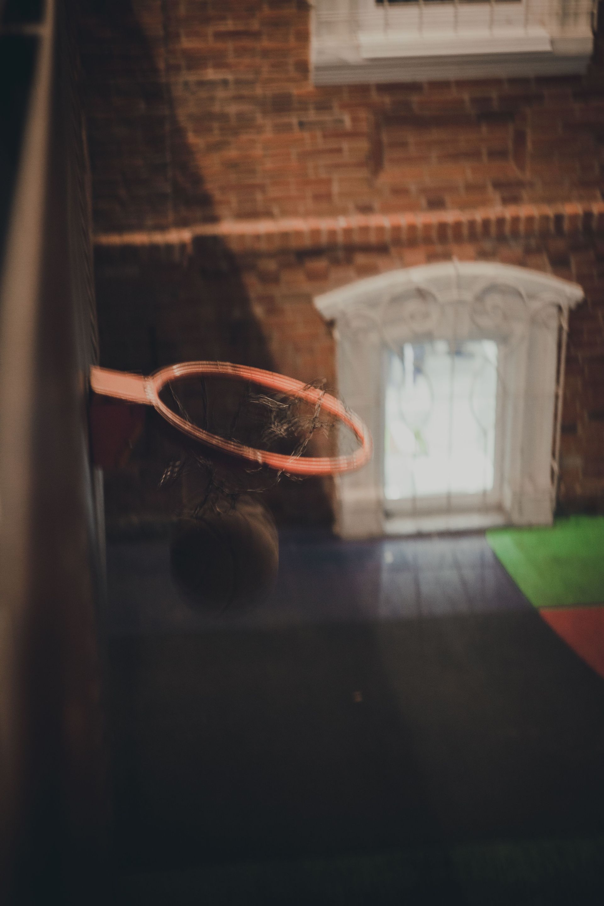 Basketball hoop mounted on a brick wall beside an arched window