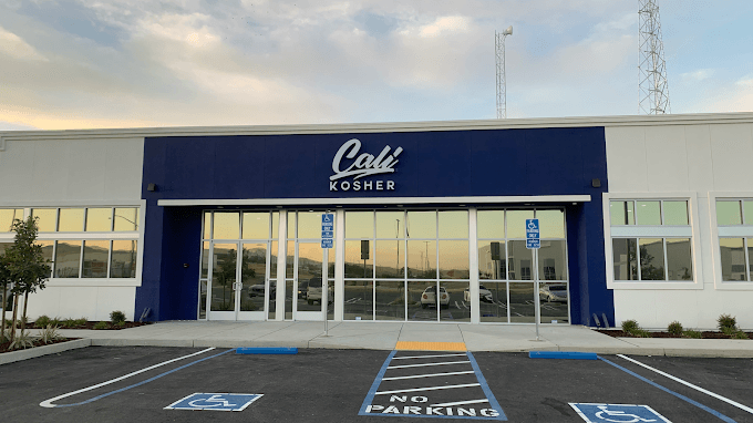 Front entrance of a Cali Kosher in Patterson with blue facade and accessible parking spaces outside