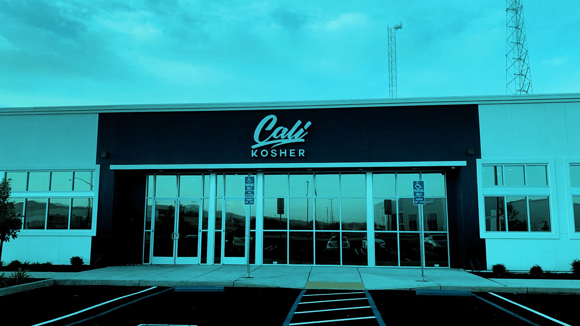 Front entrance of Cali Kosher’s Patterson dispensary, featuring a black-and-white facade and accessible parking spaces.