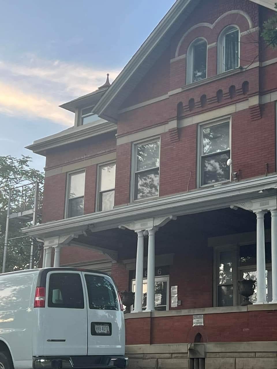A white van is parked in front of a large brick building