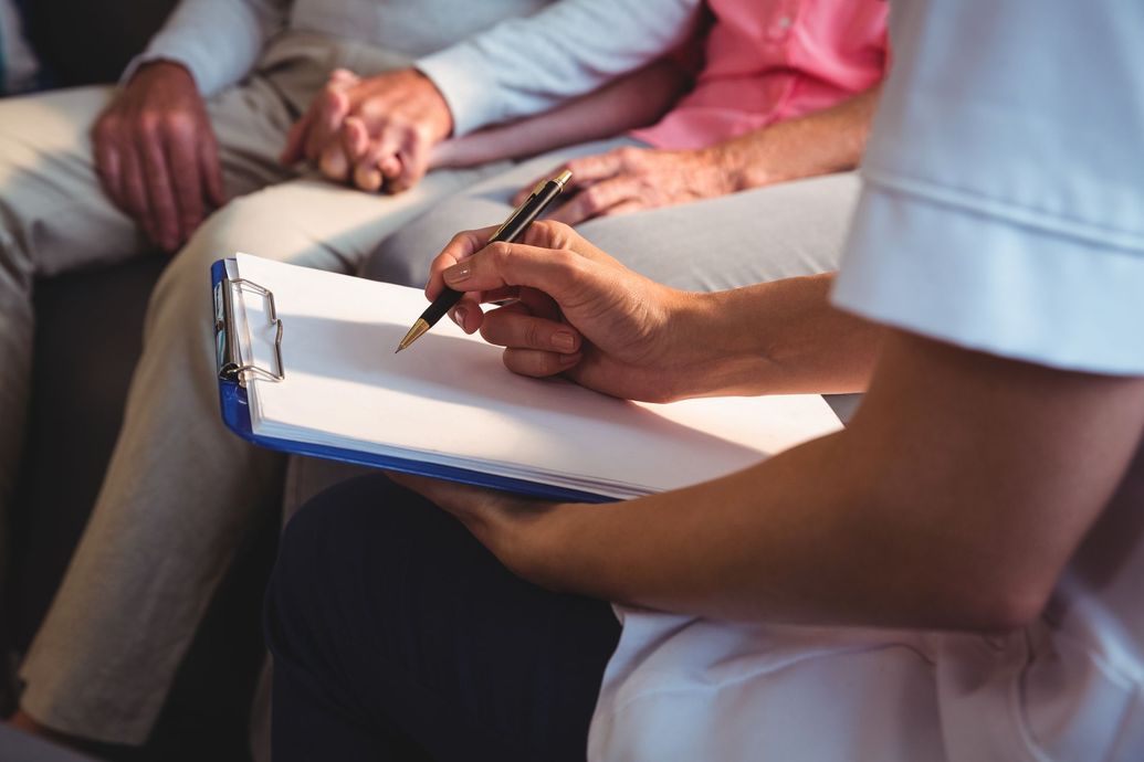 A nurse is writing on a clipboard in front of a group of elderly people.