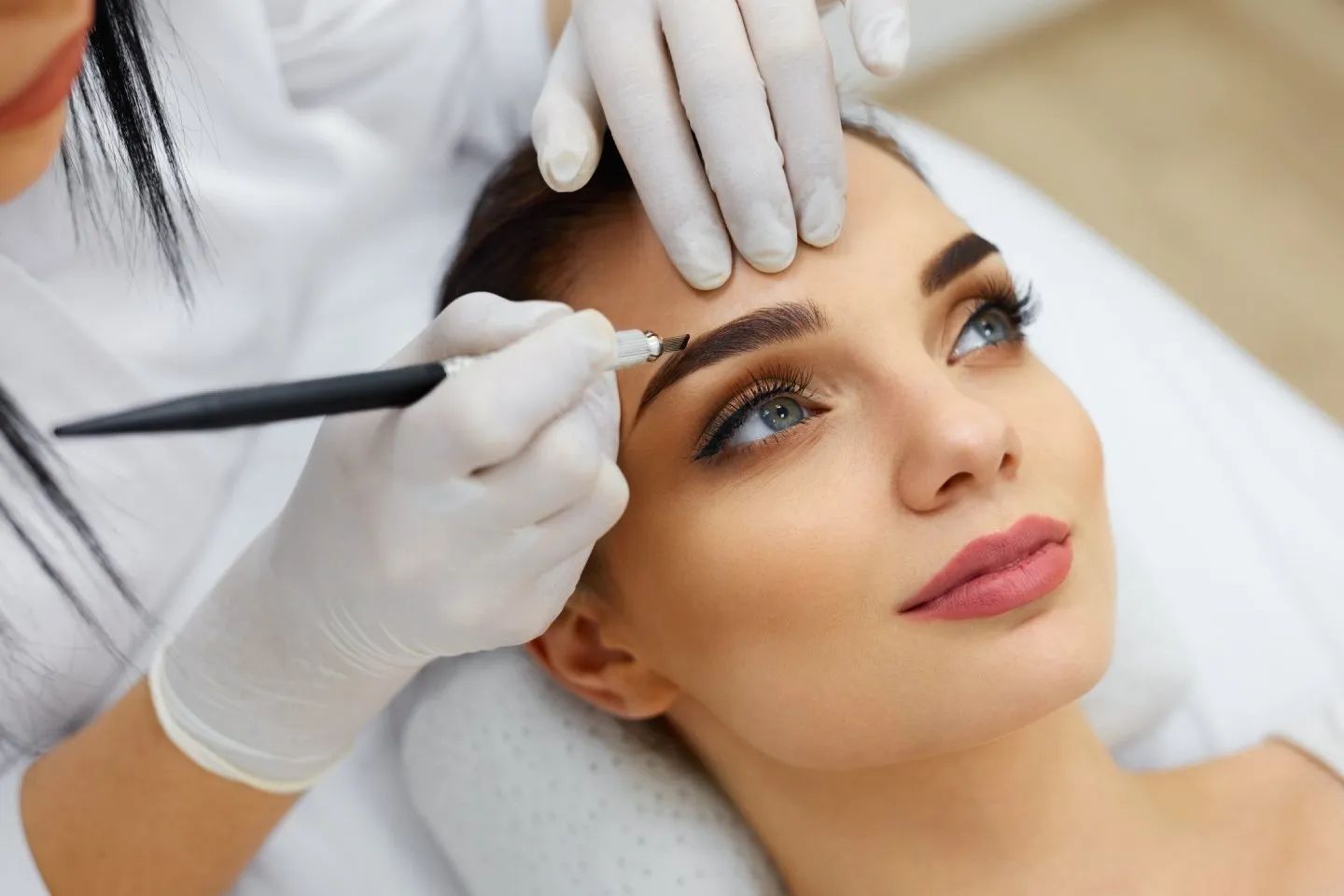 a woman is getting her eyebrows done by a professional