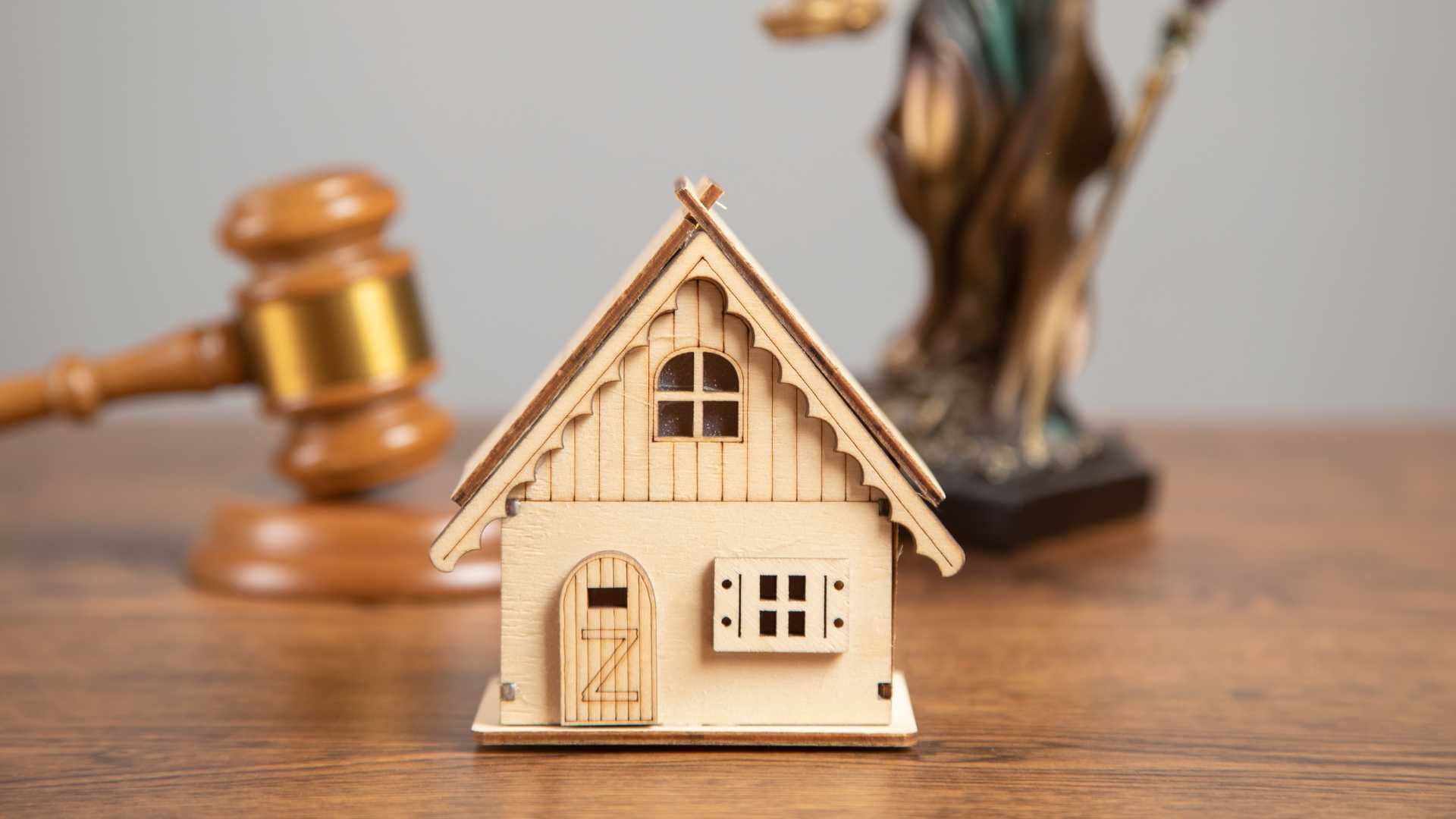 a small wooden house is sitting on a wooden table next to a judge 's gavel .