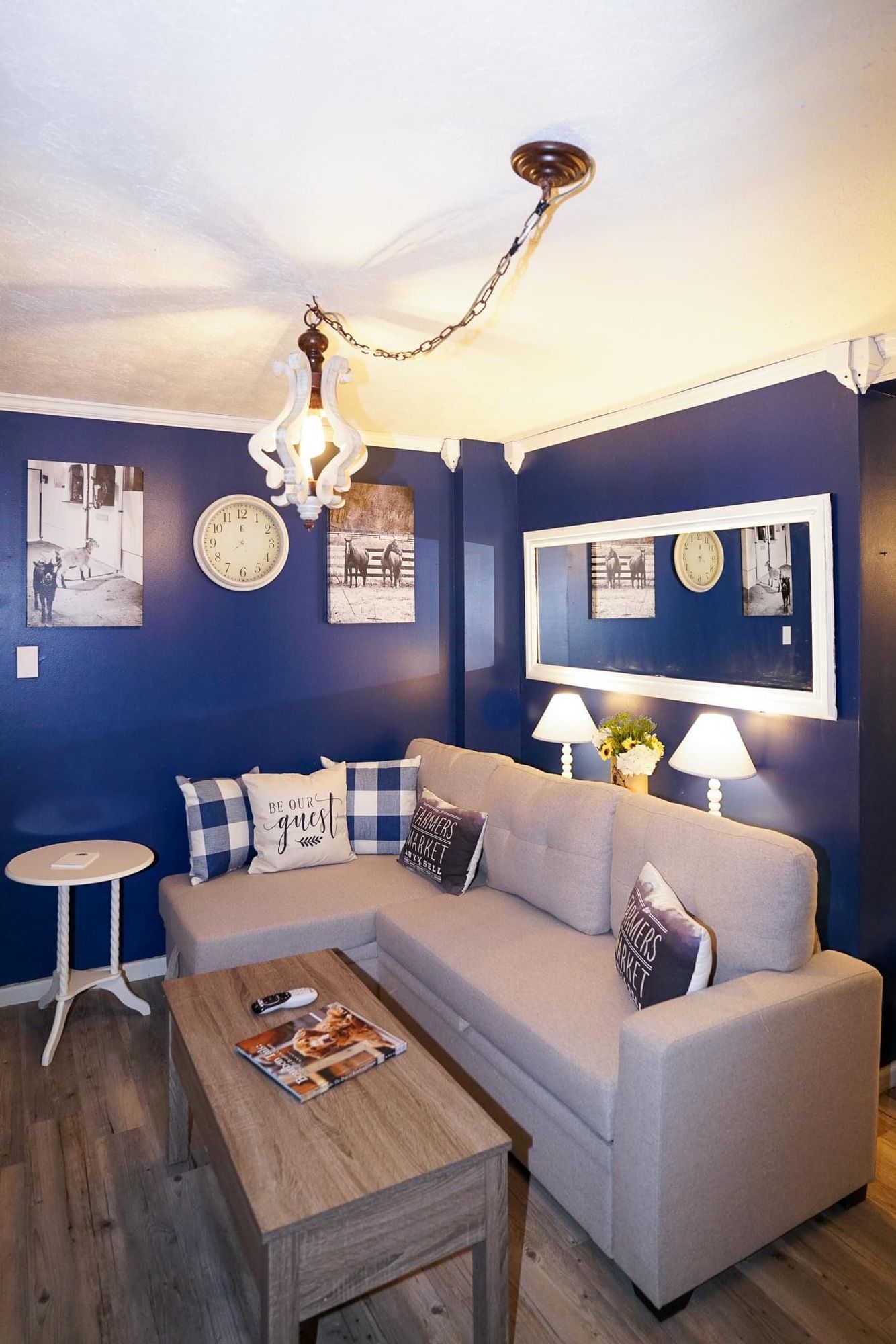 Cozy living room with blue walls, gray sofa, wood coffee table, and warm overhead lighting