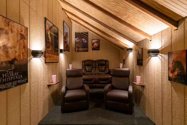 Cozy attic home theater with three recliner seats, warm wood walls, and framed art on both sides