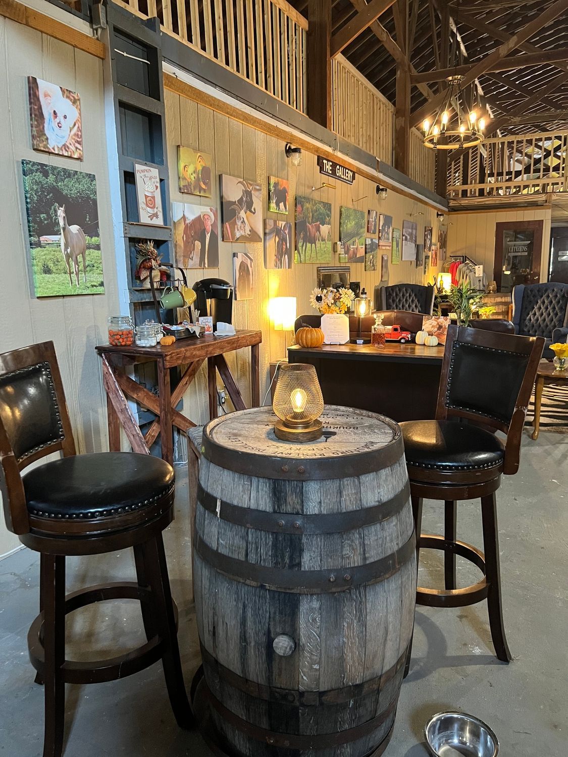 Rustic bar interior with barrel table, stools, and warm hanging lights