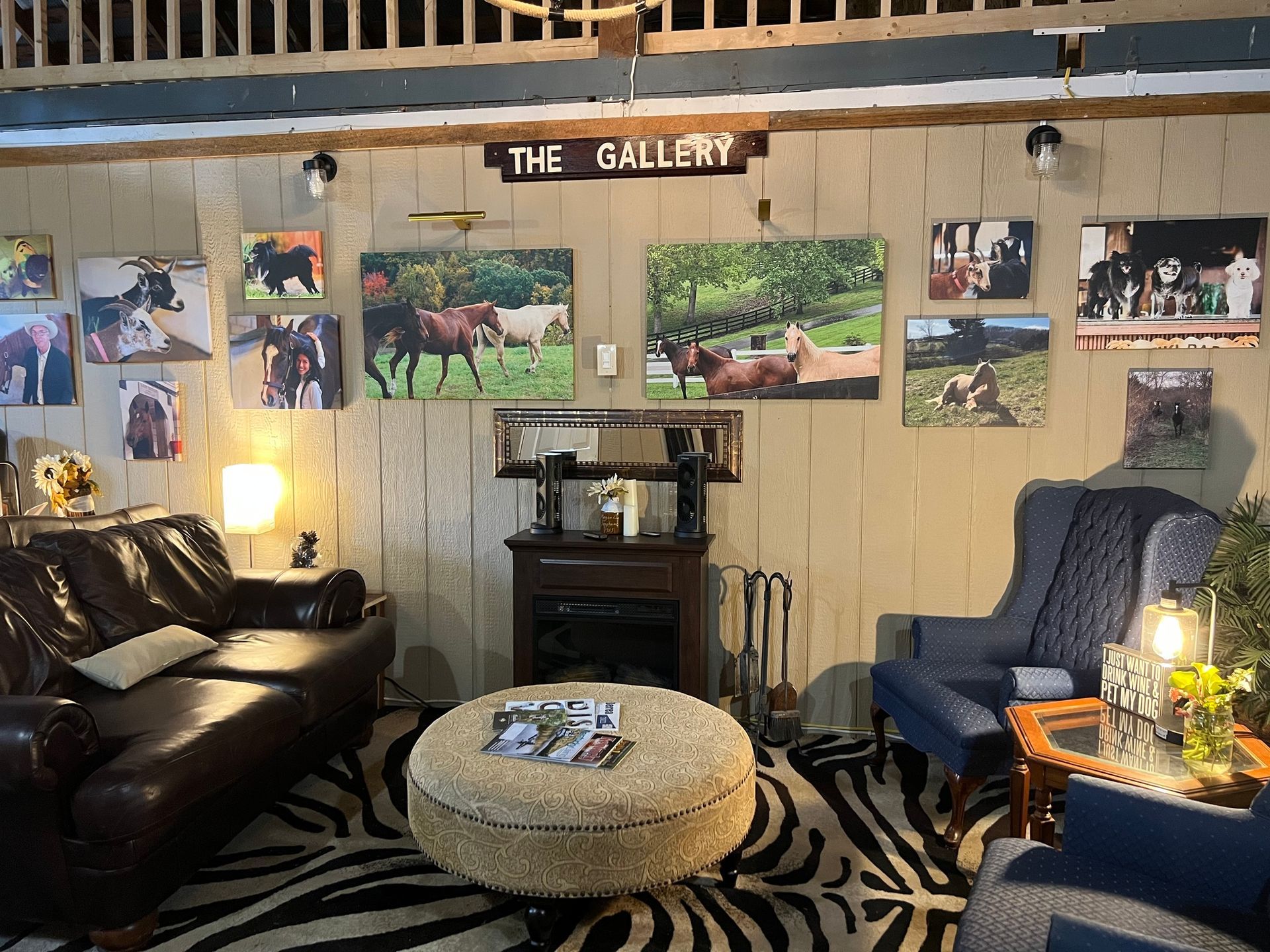 Cozy gallery-style room with leather sofa, blue chair, zebra rug, and photo collage walls.