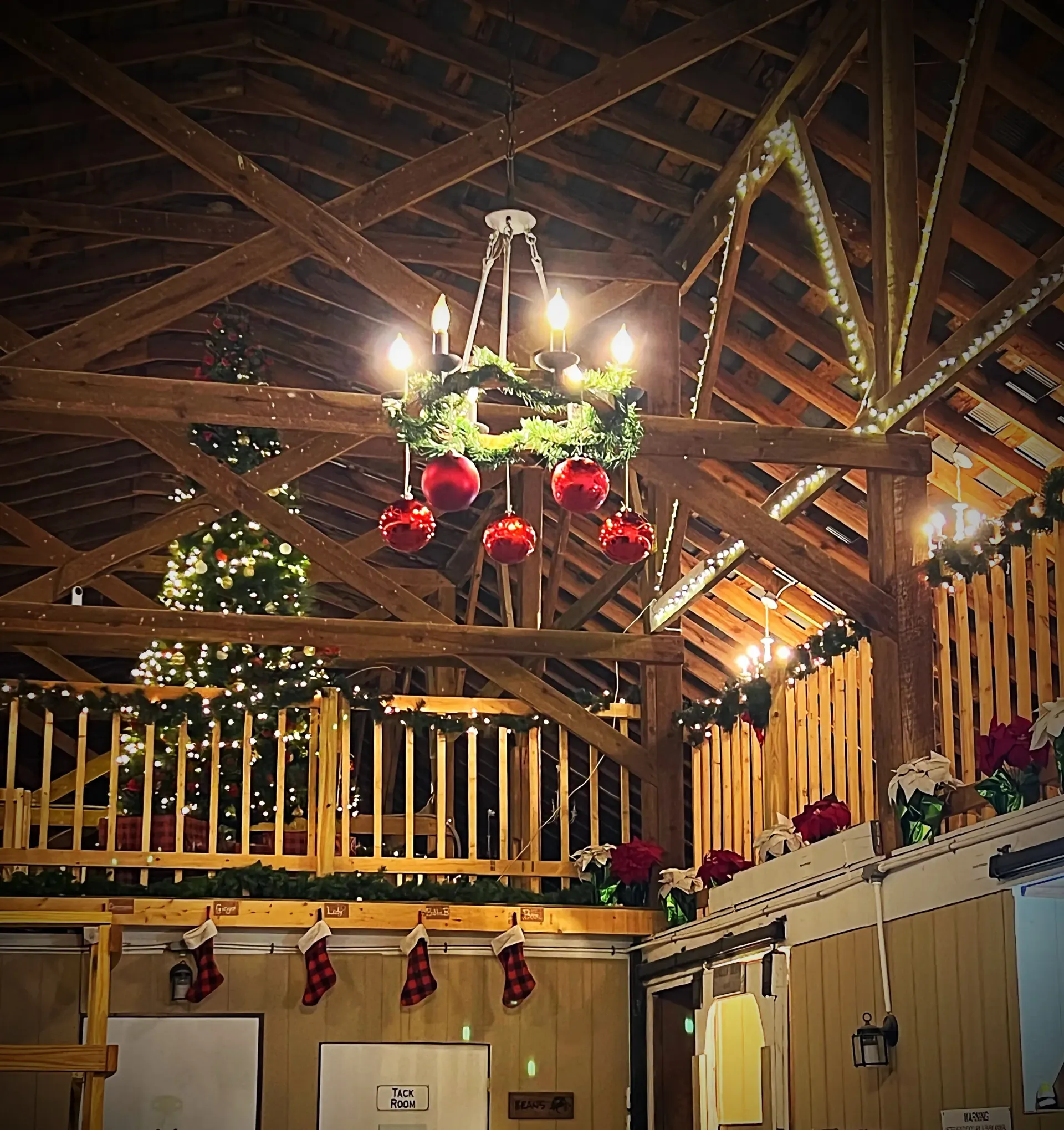Rustic lodge interior with exposed beams, hanging red ornaments, and warm holiday lights