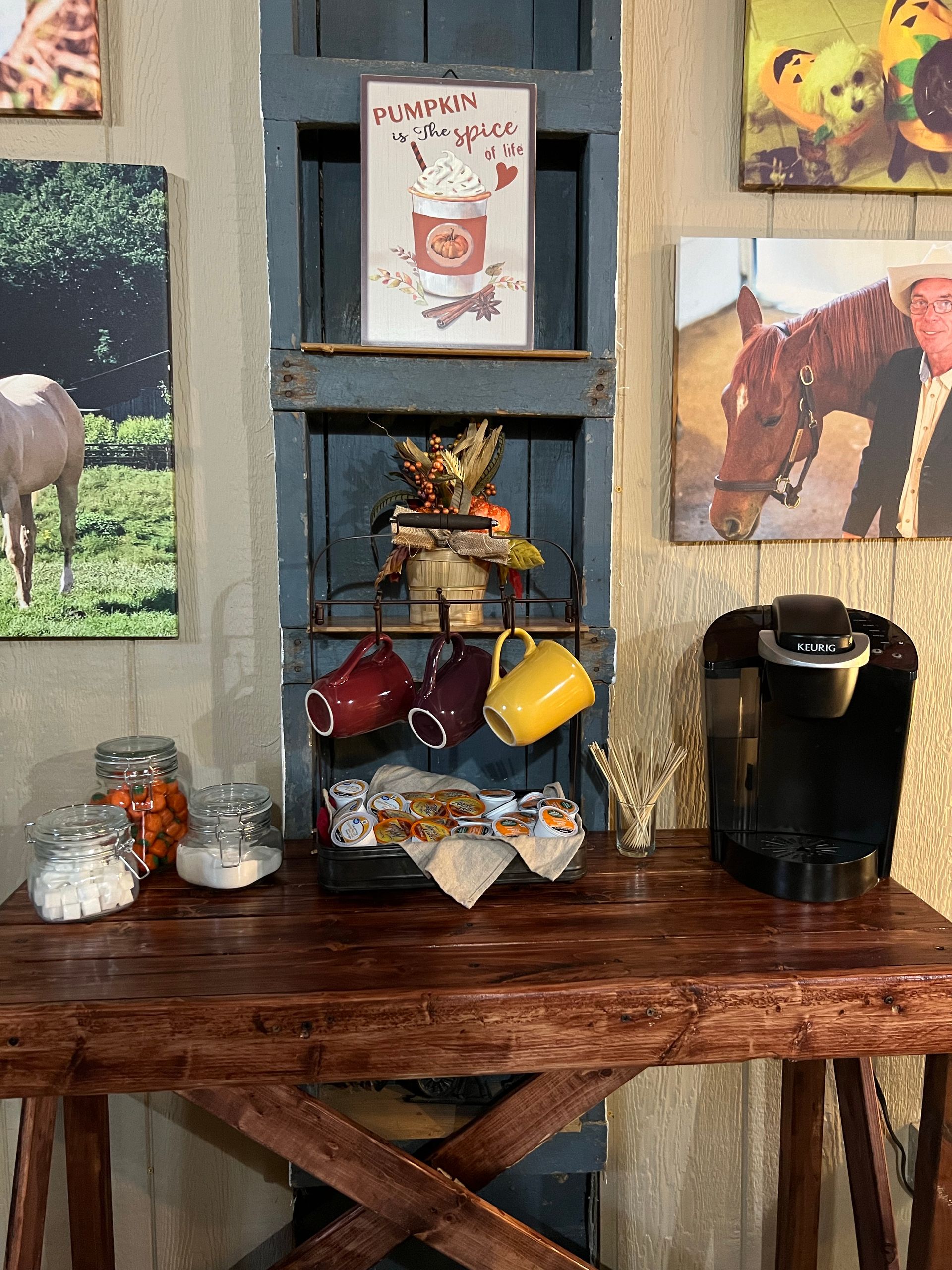 Rustic coffee station with mugs, a black coffee maker, and wall art above a wooden table