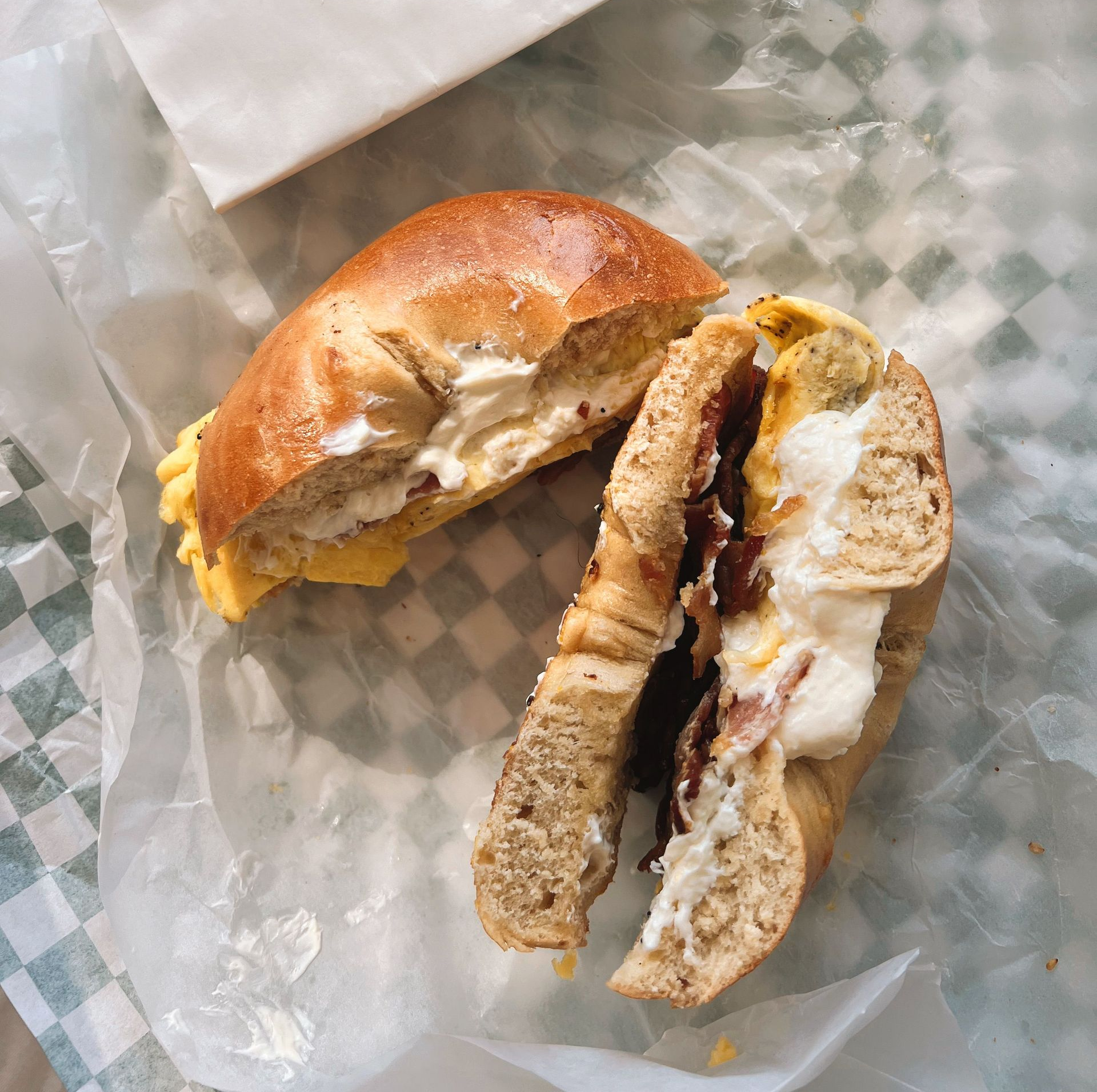 Partially eaten sandwich on checkered paper wrapping
