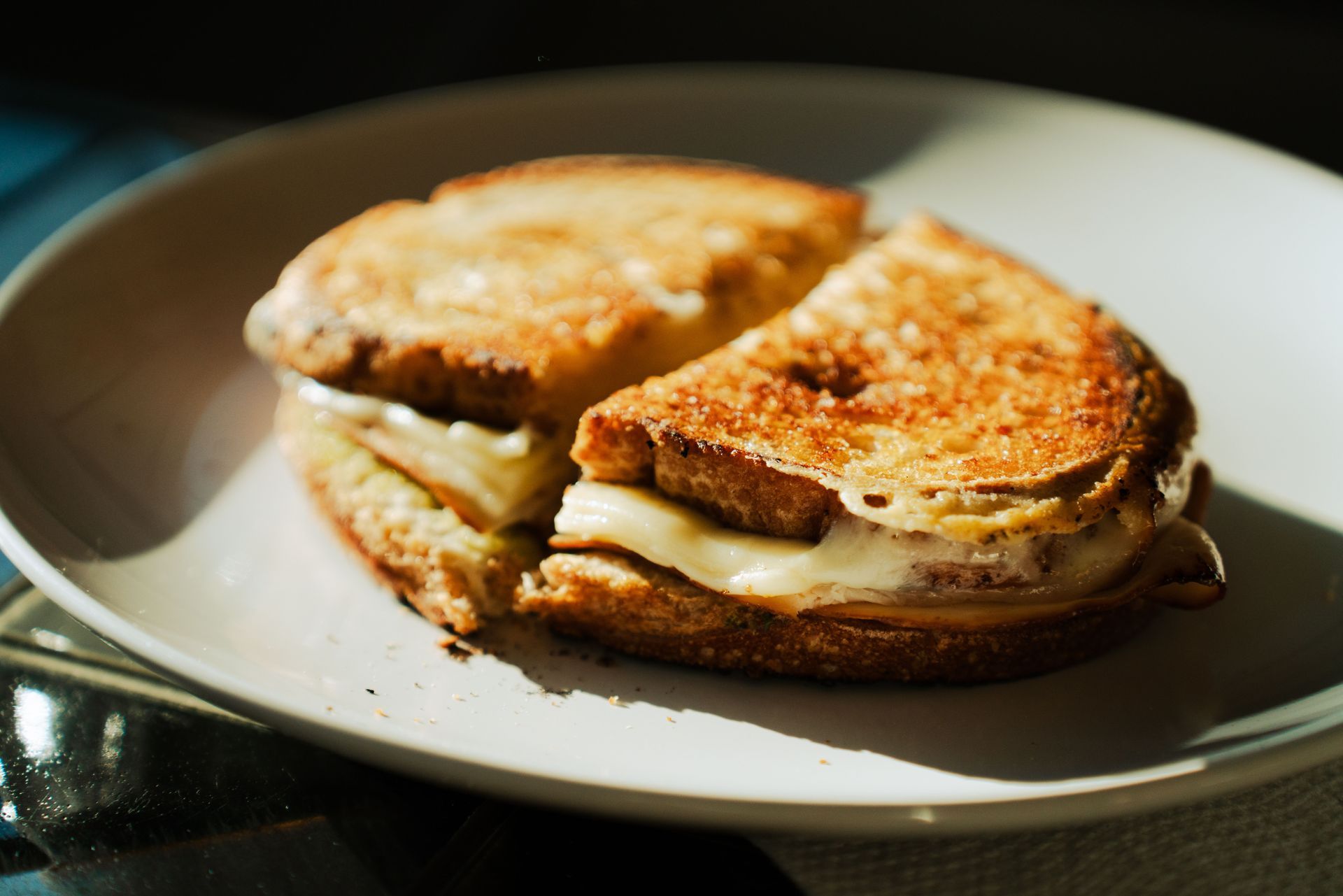 Grilled cheese sandwich halves on a white plate, golden brown and slightly melted.