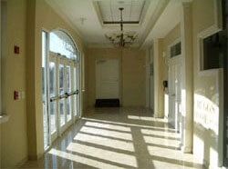 Hallway with glass doors, light walls, and shadows cast by sunlight.