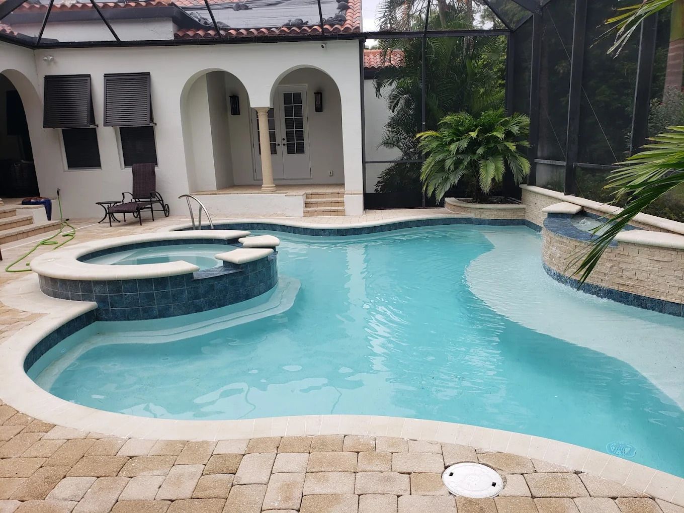 A large swimming pool with a hot tub in the backyard of a house.