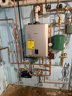 Wall-mounted boiler and copper piping in a utility room, with green expansion tank and gauges