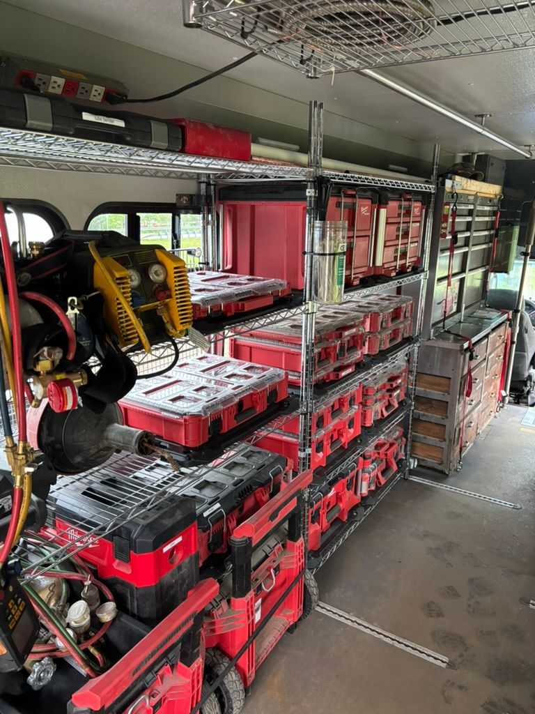 Interior of a bus with stacked red toolboxes and equipment shelves along the aisle