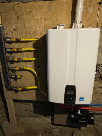 Wall-mounted white boiler with yellow pipes in a basement utility room
