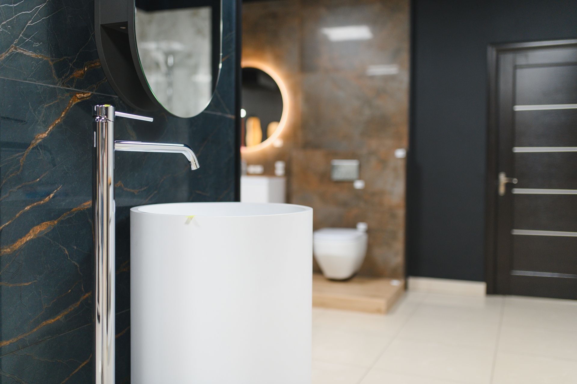 Modern bathroom with white sink, chrome faucet, and dark door in the background