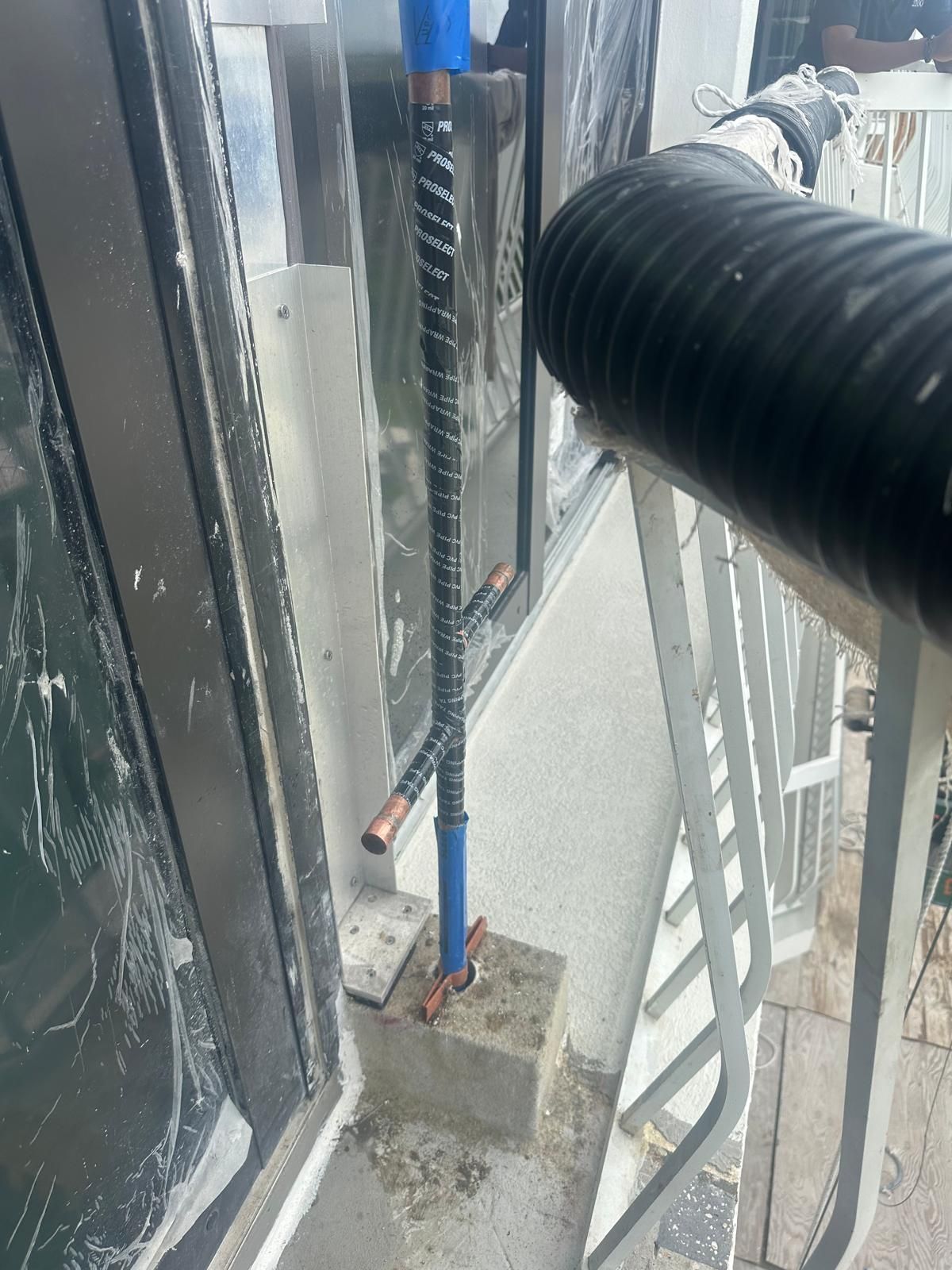 Close-up of a window-cleaning rig with a hose and pole beside a building facade and exterior stairs