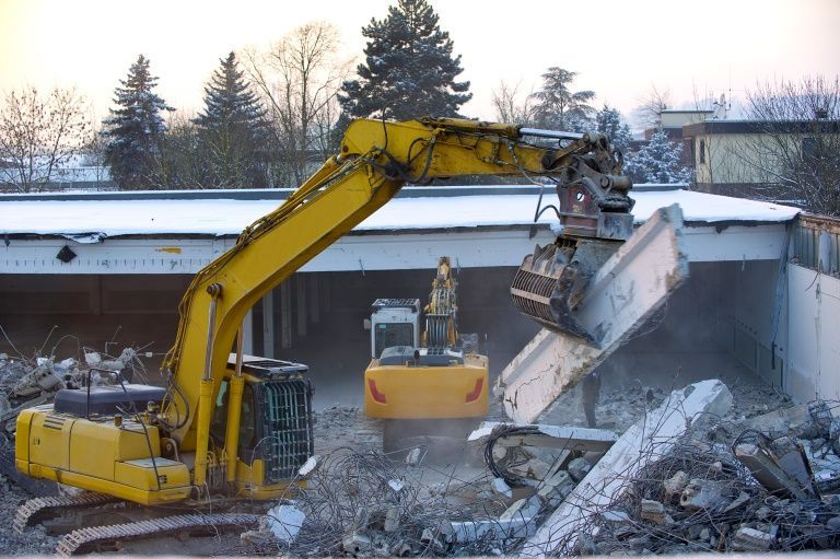 A Large Yellow Excavator is Demolishing a Building — Al's Excavation in Sunshine Coast, QLD
