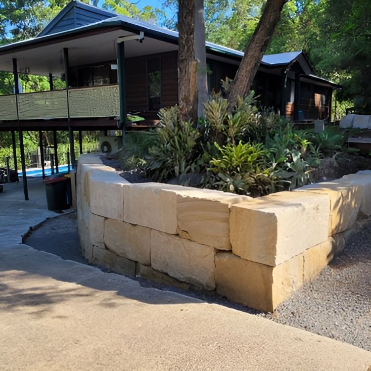 A House With a Stone Wall in Front of It — Al's Excavation in Bridges, QLD