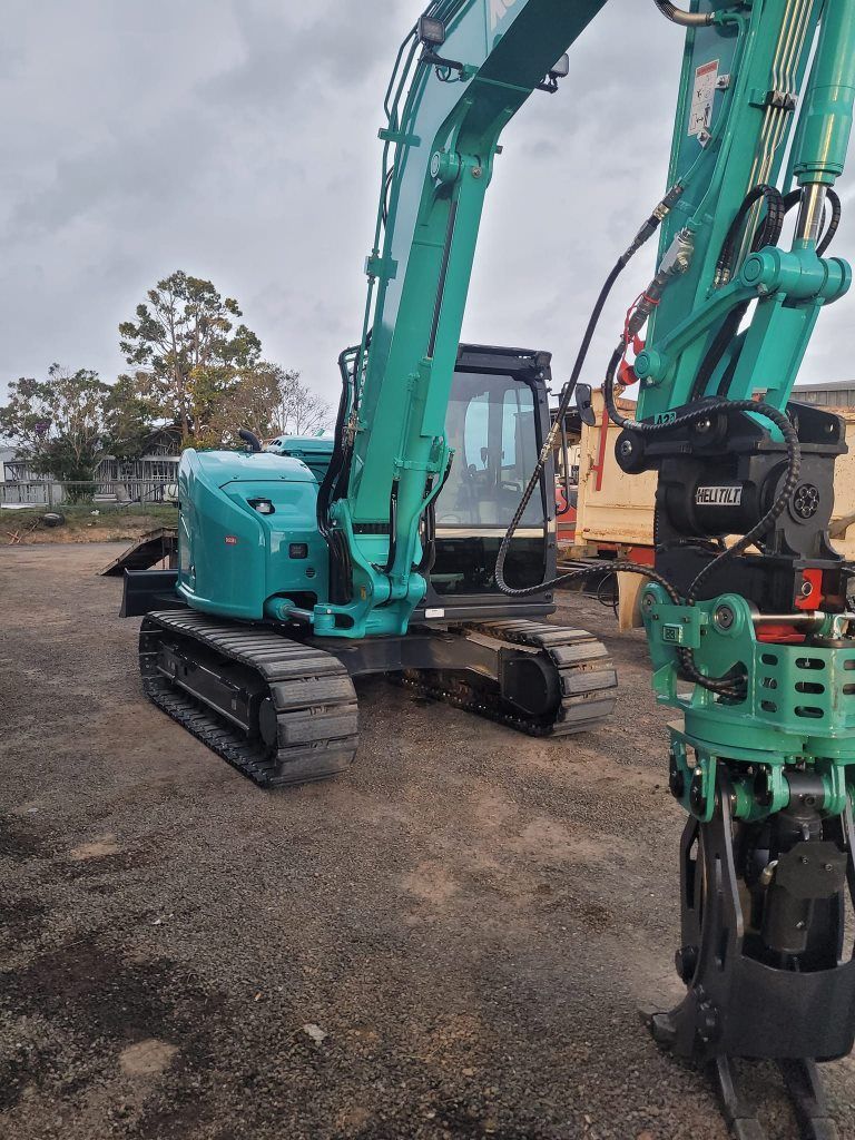 A green excavator is parked in a gravel lot. — Al's Excavation in Bridges, QLD