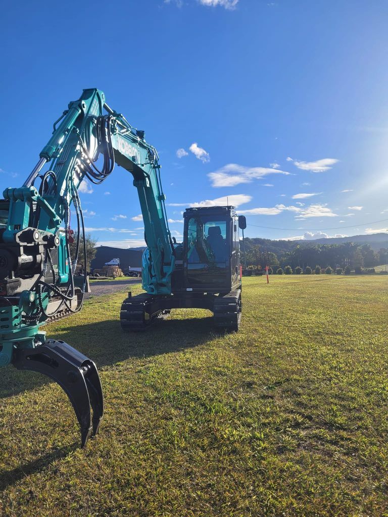 A green excavator is parked in a grassy field. — Al's Excavation in Sunshine Coast, QLD