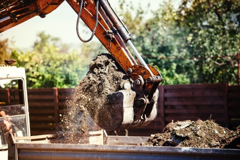 A Bulldozer is Loading Dirt Into a Truck — Al's Excavation in Sunshine Coast, QLD