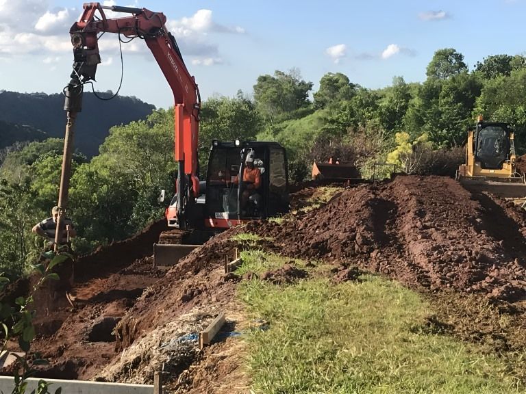 A bulldozer is digging a hole in the ground — Al's Excavation in Sunshine Coast, QLD