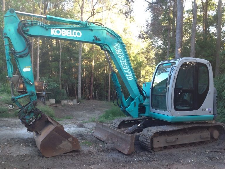 A kobelco excavator is parked in the middle of a forest — Al's Excavation in Sunshine Coast, QLD