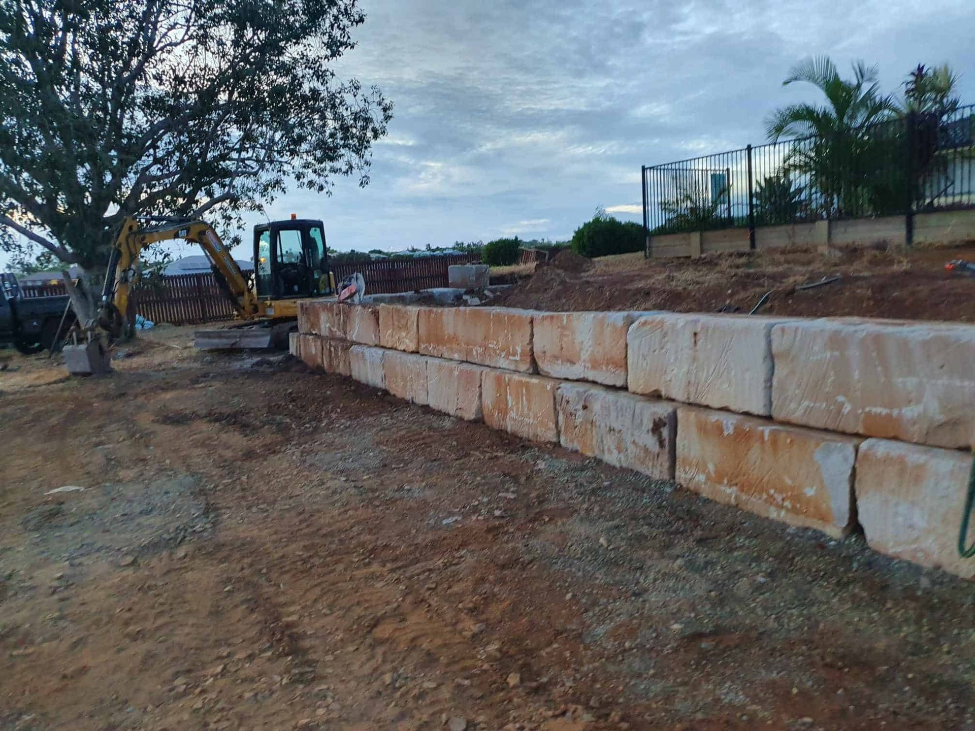 A Man is Standing in Front of a Large Rock Wall in Front of a House — Al's Excavation in Sunshine Coast, QLD