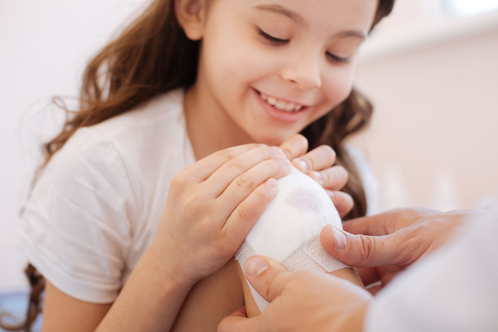 Child smiling while getting knee bandaged