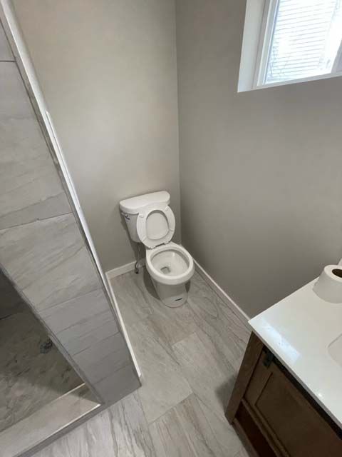 A bathroom with a toilet , sink and shower.