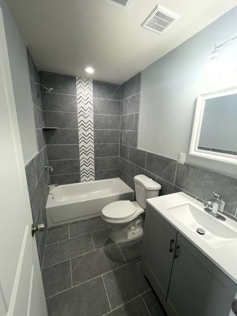 A bathroom with a toilet , sink , bathtub and mirror.