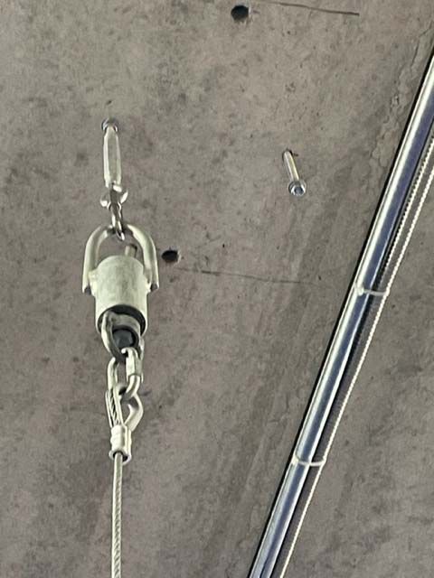 A metal hook is hanging from a concrete ceiling