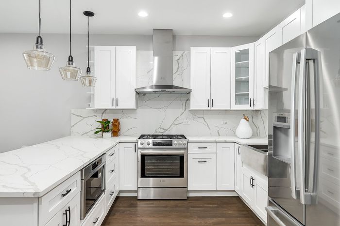 A kitchen with white cabinets , stainless steel appliances , and a large island.