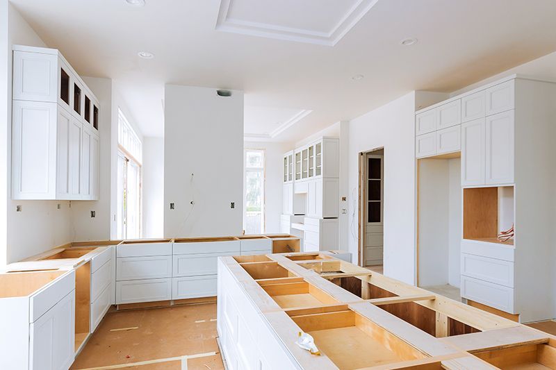 A kitchen under construction with white cabinets and wooden counter tops.