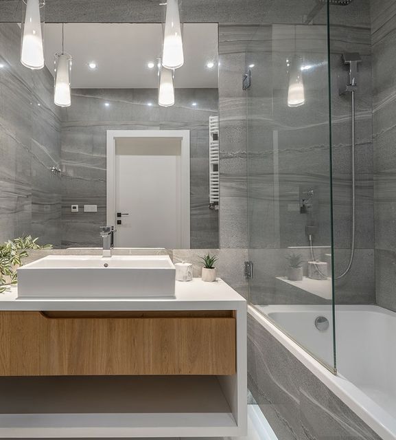 A bathroom with a sink , tub , shower and mirror.