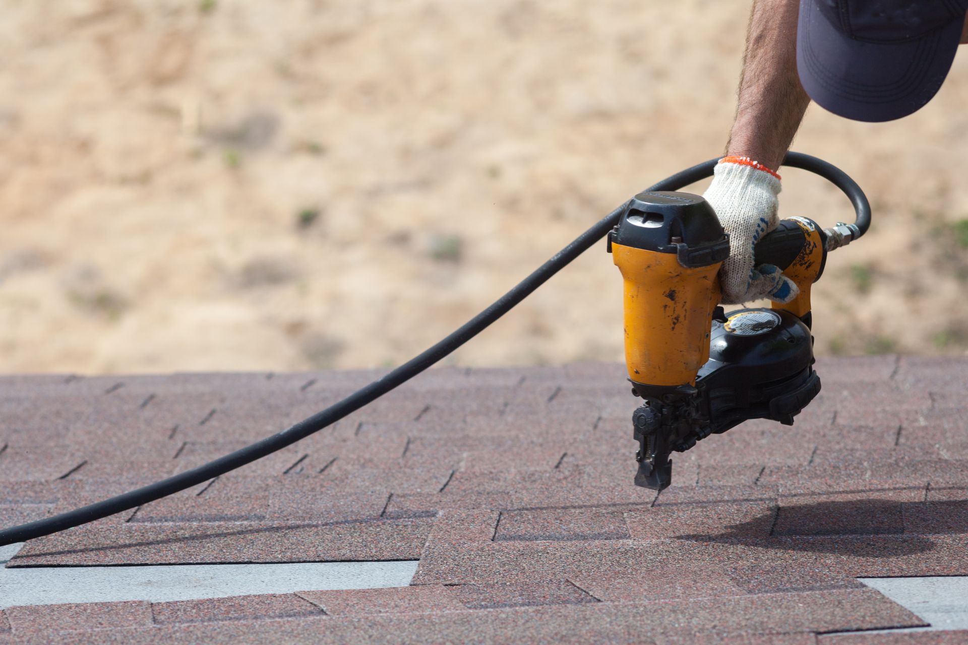 Person using a nail gun to install roofing shingles. Person using a nail gun to install roofing shingles.
