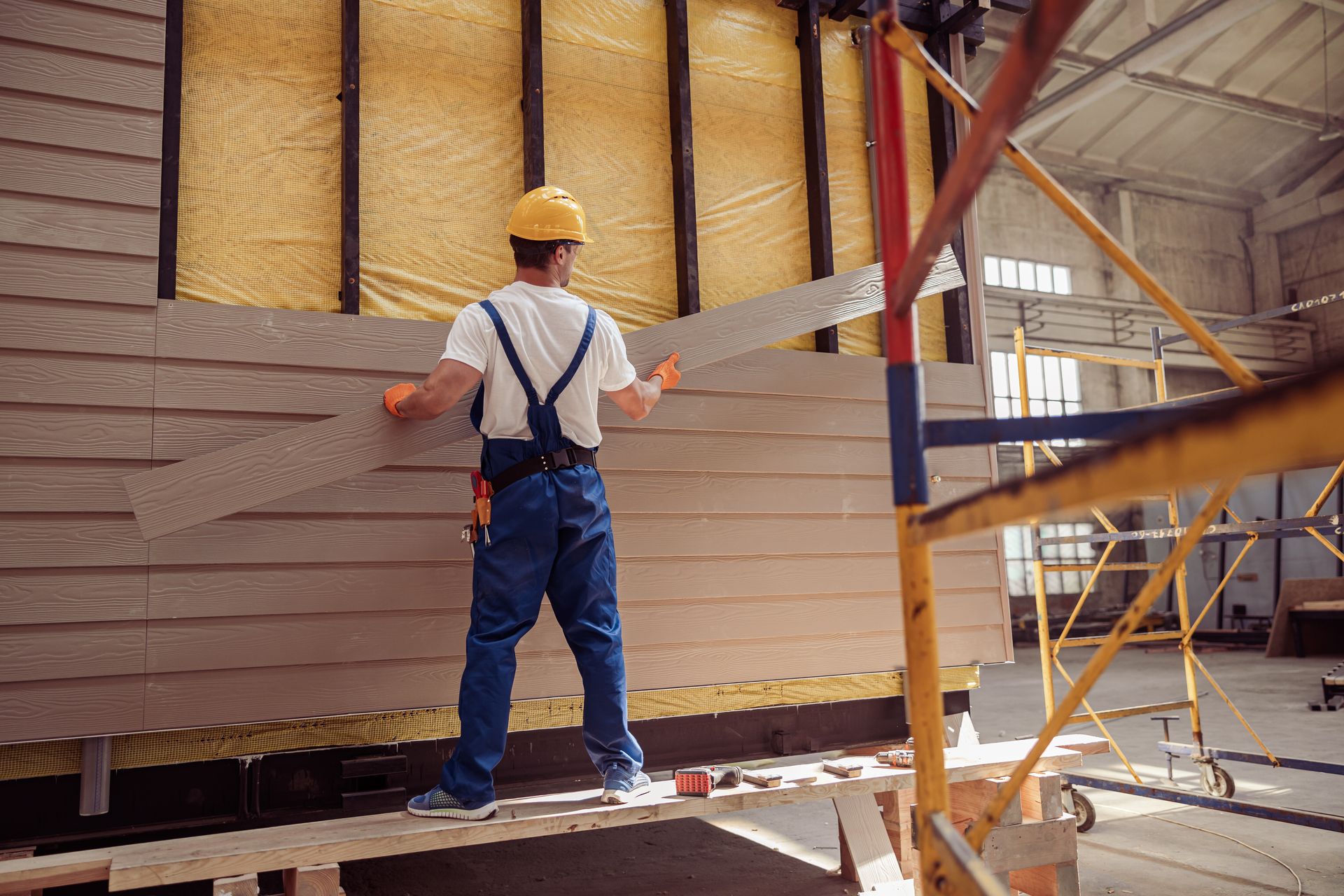Construction Worker Installing Siding From Scaffolding