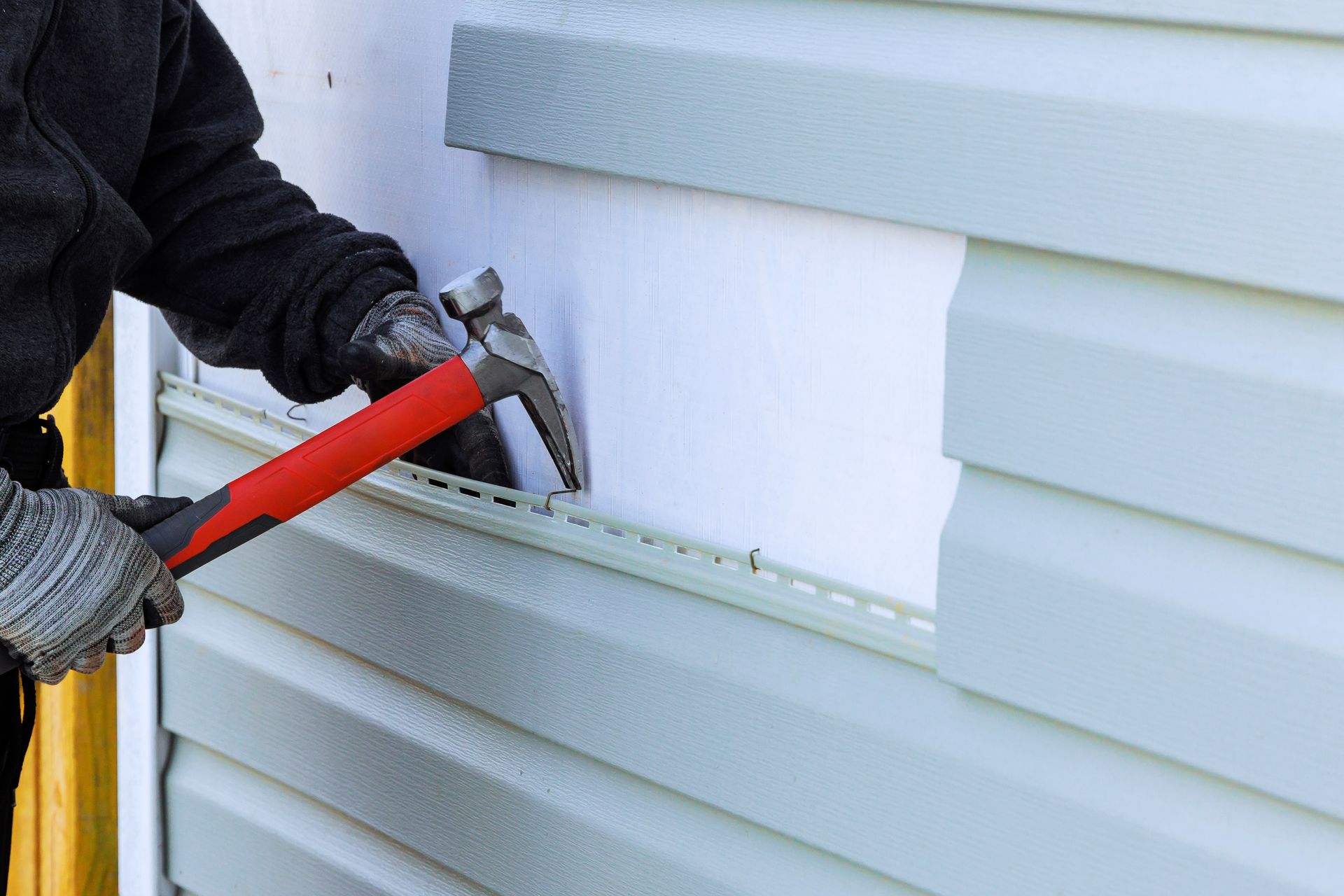 Person Removing Siding With Hammer