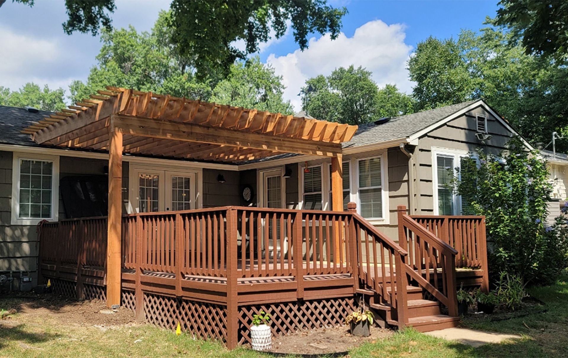 A house with a large wooden deck and a pergola.