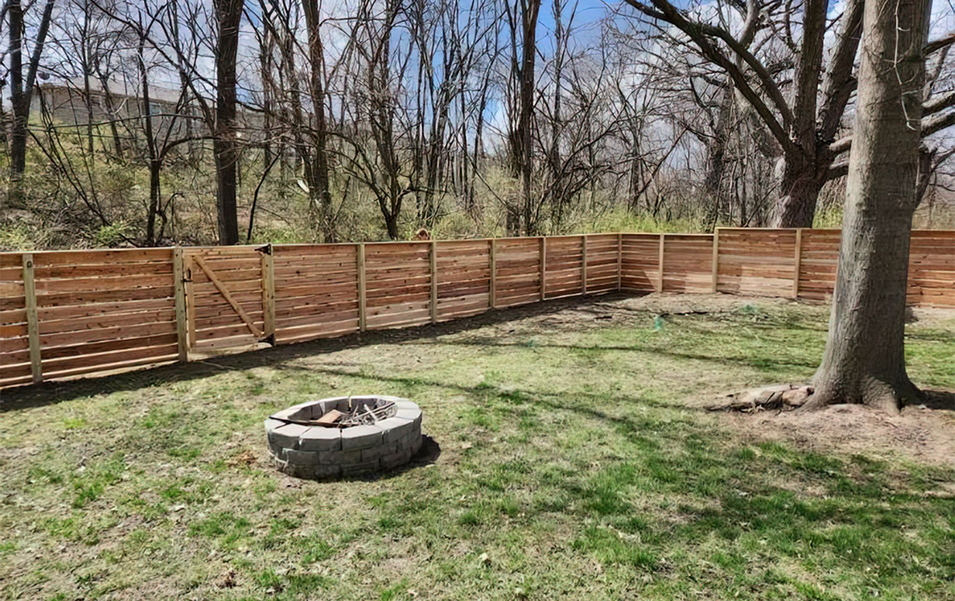 A wooden fence is in the backyard of a house.