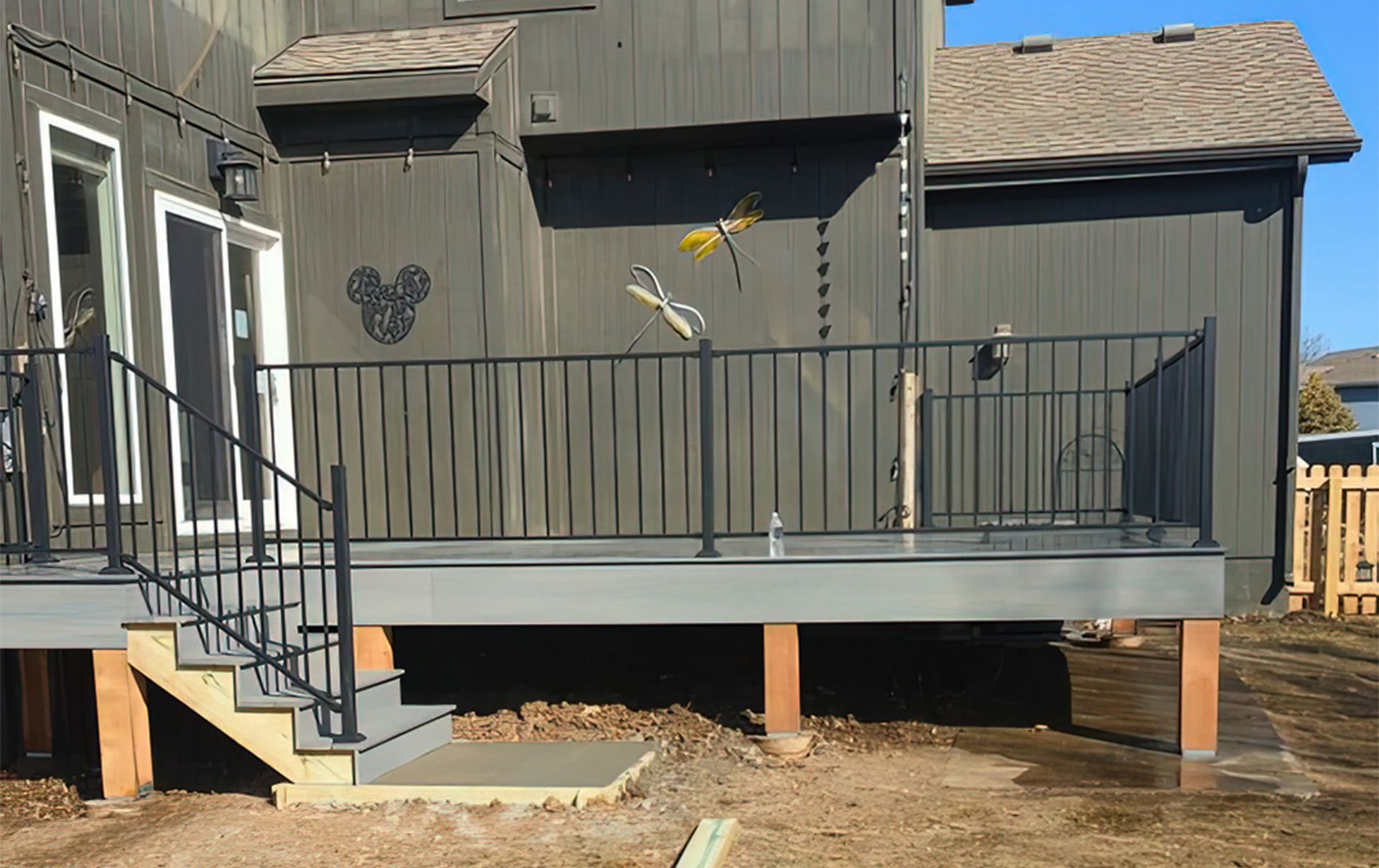 A deck with stairs and a metal railing in front of a house