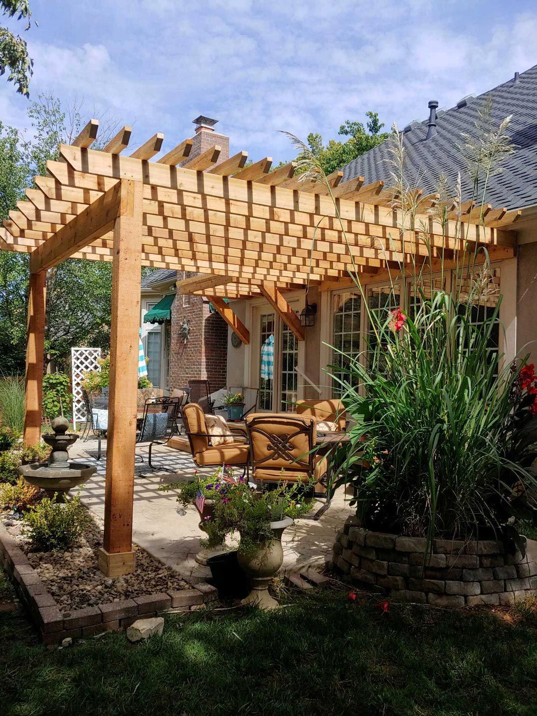 A wooden pergola is in the backyard of a house.